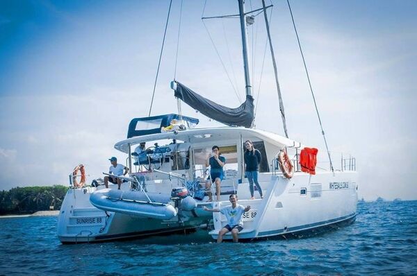 Sailing catamaran with crew and passengers relaxing on deck aboard White Sails Yacht as it heads out from Singapore towards Lazarus Island