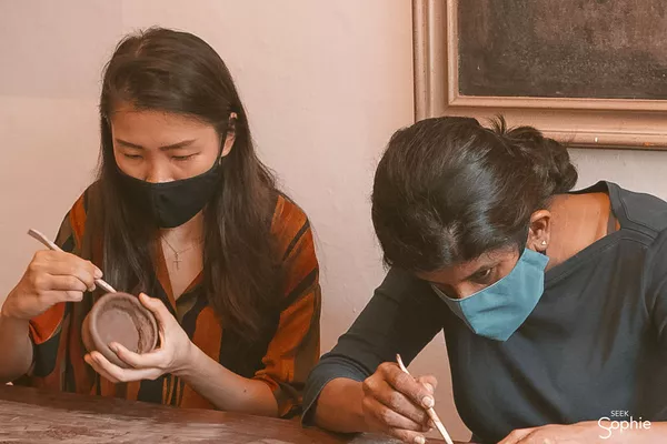 Masked students glazing ceramic bowls at Dirty Hands Only pottery studio in Singapore painting details at the table — workshops in Singapore