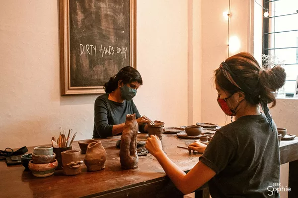 Students handbuilding ceramic pieces at Dirty Hands Only pottery studio in Singapore, shaping clay at a workbench — workshops in Singapore