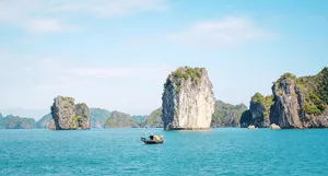Open-water view of limestone islets with a small boat on Cat Ba Bay, part of a 3D2N Cat Ba cruise