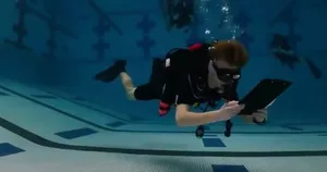 Underwater training pool scene with a diver reading a slate while practising open-water skills for Sanctum Dive Indonesia in Bali