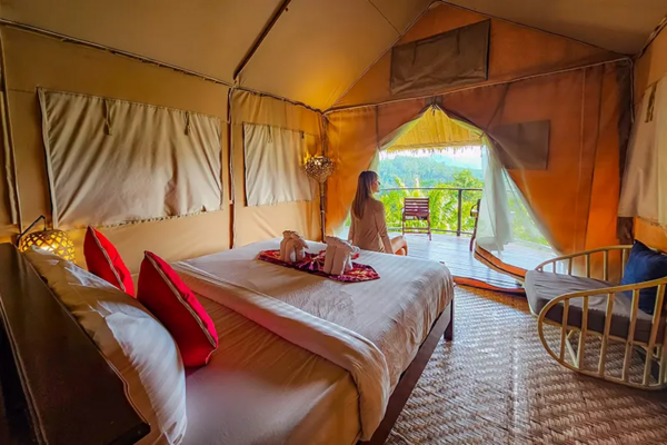 Khaosok Discovery luxe glamping tent with a queen bed and a guest relaxing, facing green valley views in Khao Sok National Park