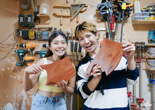 Two smiling participants holding finished wooden cheese boards from a Singapore private woodworking class, workshops in Singapore