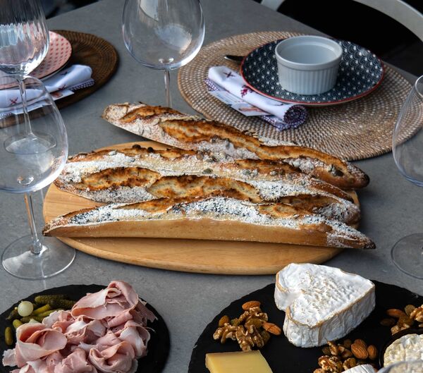 Baked baguettes with a French chef’s sunset charcuterie spread, wine glasses and cheese on a table for workshops in Singapore