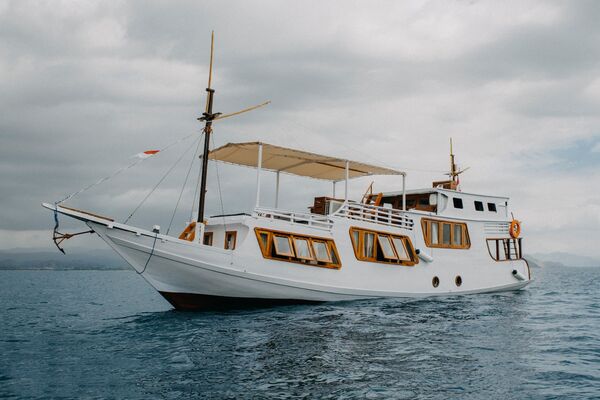 Side view of a cosy phinisi anchored off the coast with deck windows and railings on a private 3D2N couple trip, Komodo Island