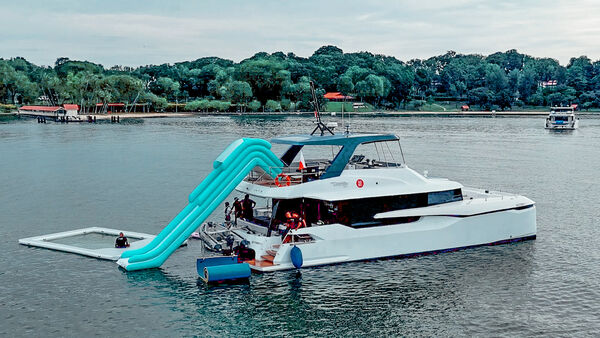 MS Eternity catamaran moored on a calm Singapore waterway with bright blue inflatable slide, ready for a 4-hour Lazarus cruise