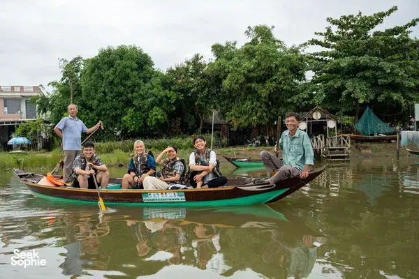 Small-group boat trip with people in life jackets on a green wooden vessel through Hoi An during Xom Tour’s journey