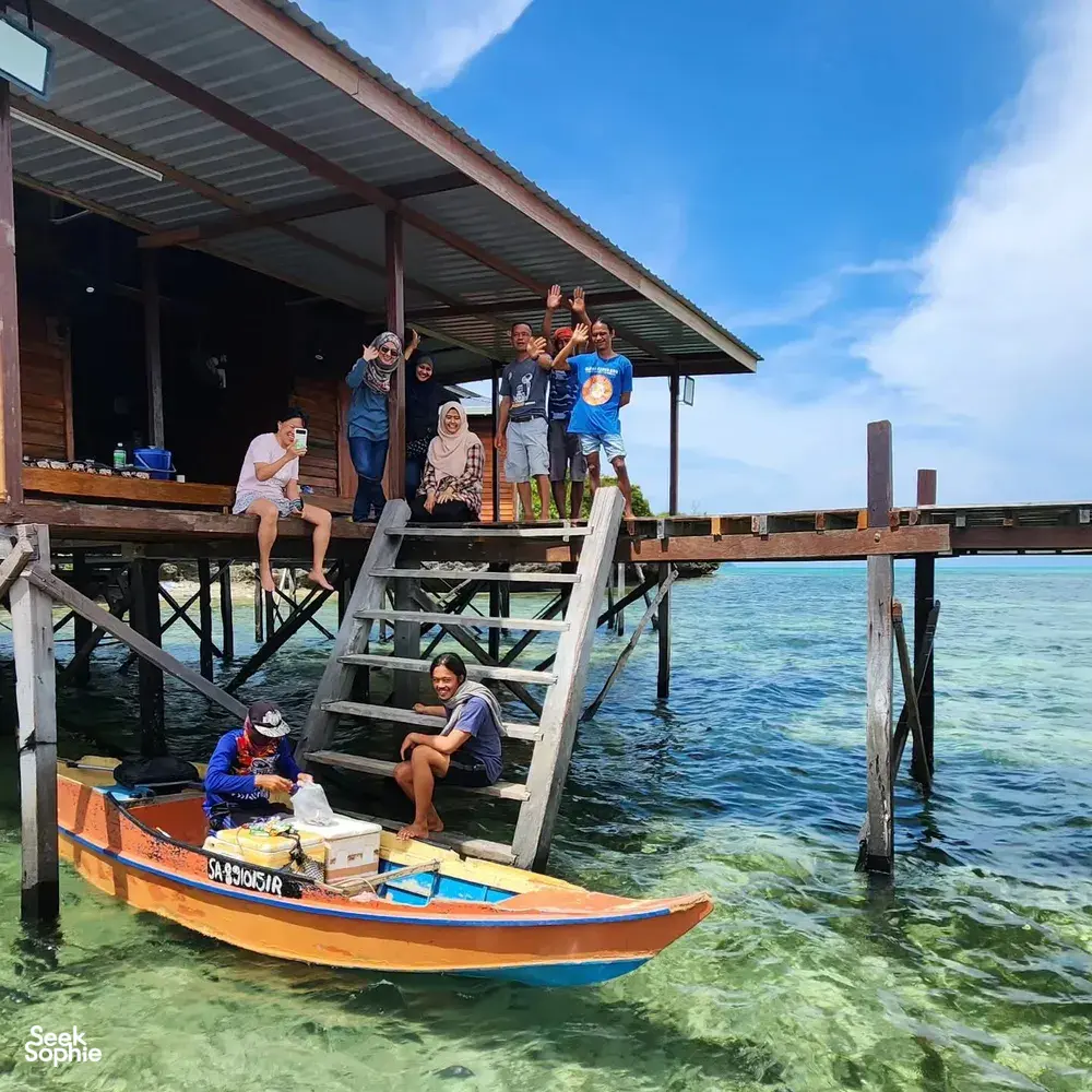 Diving group posing on a small boat beside the jetty at Luma Selakan sea lodge in Semporna, ready to explore