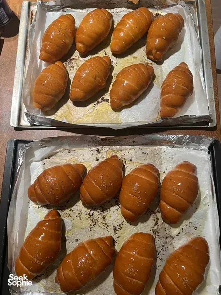 Glazed shio pan rolls filling two parchment-lined trays as they cool after baking during workshops in Singapore