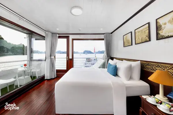 Cabin interior on the Oasis Bay Party Cruiser with a double bed, cushions and large windows viewing the bay during Halong Bay