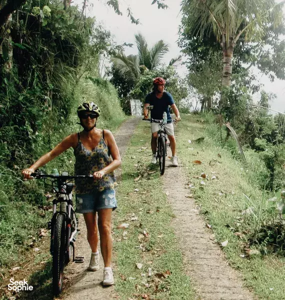 Cyclist on an e-bike on a jungle track near Jatiluwih rice terraces, with another rider following on a Green Bikes Bali tour