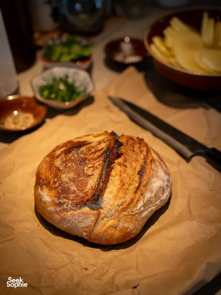 Crusty bread loaf on parchment with small side dishes on a dining table, set up for tapas sharing during private dining Singapore