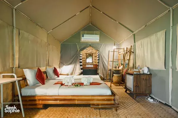 Cozy glamping tent interior with a double bed, patterned rug, and warm lighting inside a camping base in Thailand