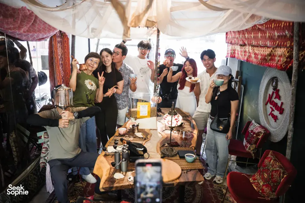 Group smiling around coffee and bagel brunch tables under a tent canopy during hands-on coffee roasting workshops in Singapore
