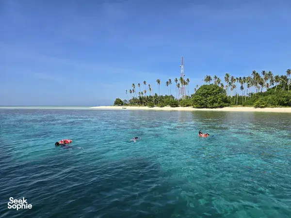 Snorkel day on Semporna’s islands: red kayaks near a palm-lined sandbar above clear turquoise water, with Bigfin Divers