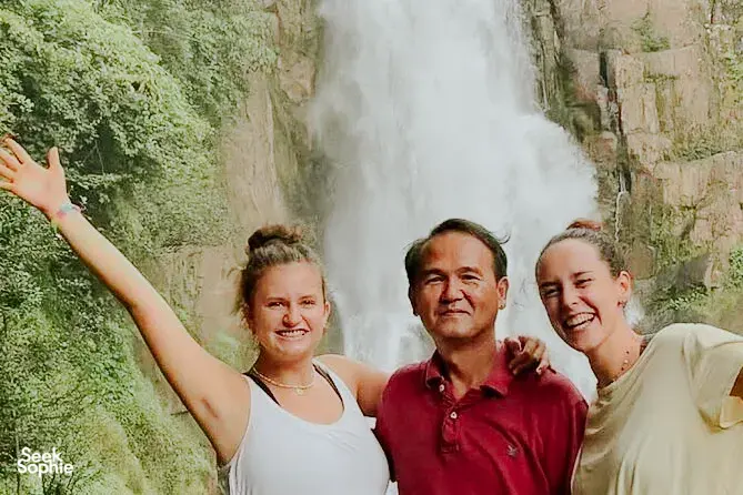 Smiling travellers posing at a waterfall in Khao Yai National Park during the wildlife trek experience