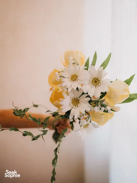Close-up of a hand-crafted lifelike paper flower bouquet with green leaves against a soft wall, for workshops in Singapore