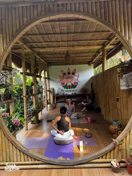 Private yoga in a bamboo garden pavilion in Bali with Pranasanti Yoga, relaxing under a circular doorway in Ubud