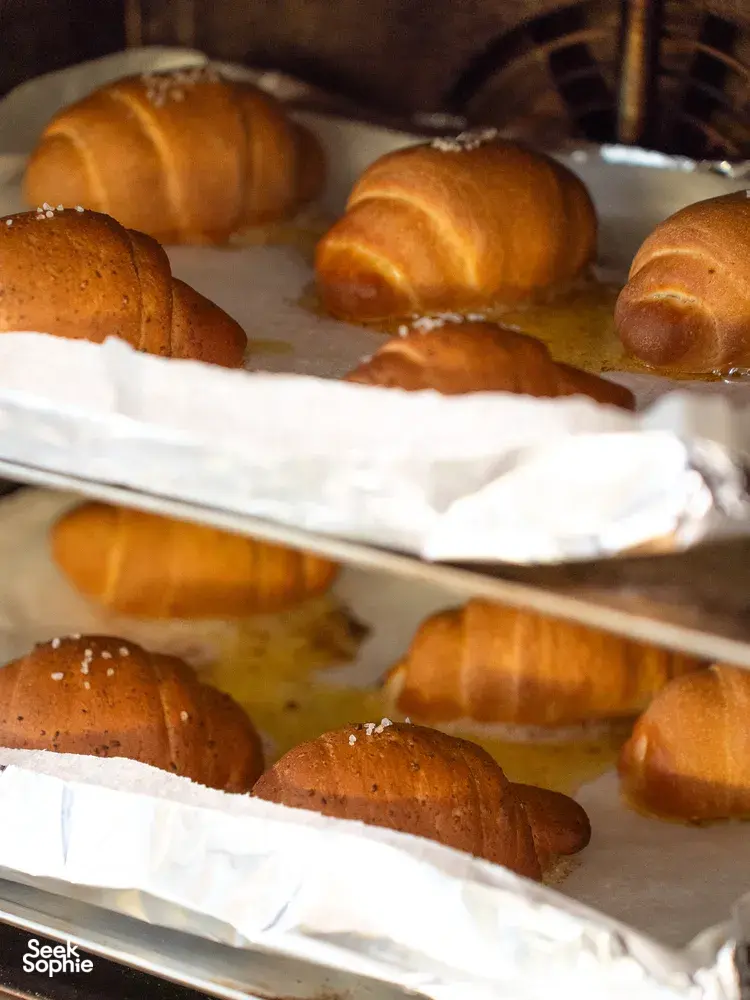 Golden shio pan buns cooling on lined trays on wooden racks inside the bakery for hands-on workshops in Singapore