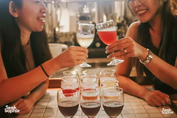 Friends clinking craft beer glasses at Lion Brewery Co taproom in Singapore, savouring tastings on the brewpub tour