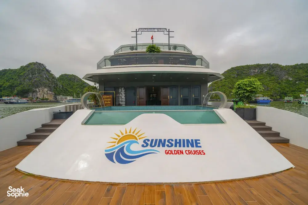 Sunshine Golden Cruises bow pool and upper deck on a luxury Cat Ba cruise, with limestone hills and cloudy skies