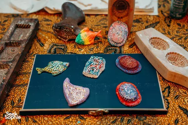 Moulded kueh sweets on a blue tray with antique baking moulds on a table during workshops in Singapore