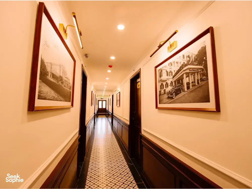 Wood-panelled corridor on a Cat Ba cruise by Sunshine Golden Cruises, lined with framed photos and patterned carpet lighting