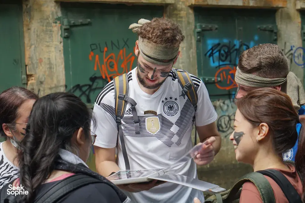 Team members listening as a guide shares clues and points at a map during Fort Serapong’s discovery quest in Singapore