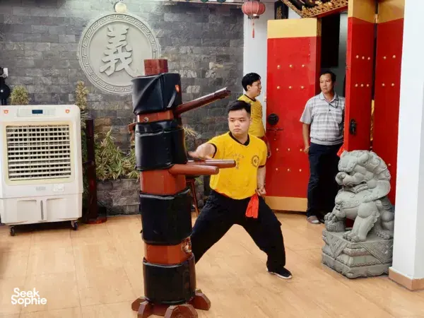 Kung fu and lion dance practice in a Ho Chi Minh City studio, learners working around a black-and-red wooden training dummy