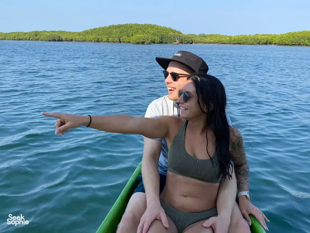 Pasangan tersenyum di atas bot menuju sesi snorkeling peribadi di Secret Gilis di luar pesisir Lombok, dengan laut yang tenang dan bukit-bukau yang menghijau