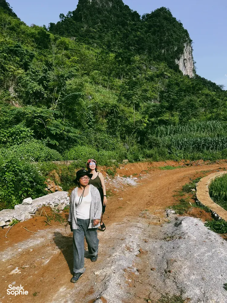 Travellers posing on a rocky roadside viewpoint with jungle hills behind during a 3D3N motorbike loop in Cao Bang