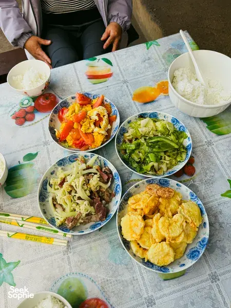 Naxi-style meal spread on a guesthouse table in Lijiang, with bowls of rice, vegetables, and stir-fry for the 2D1N trek