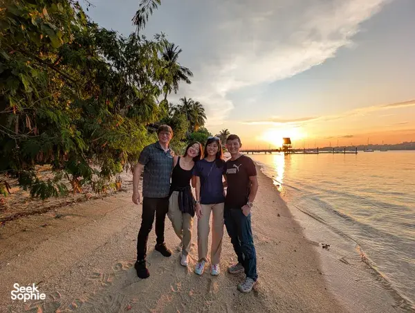 Travellers walking along a calm Singapore beach at sunset during a 2D1N farmstay by the sea with The Unexpected