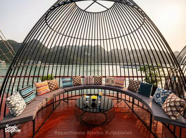 Cushioned circular seating area under a steel-and-glass dome on the Aqua of the Seas 2D1N luxury cruise in Lan Ha Bay, Halong Bay