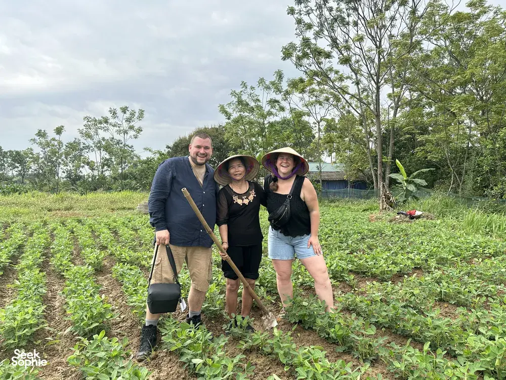 Travellers planting young rice in a muddy paddy at Duong Lam ancient village near Hanoi, led through a hands-on routine