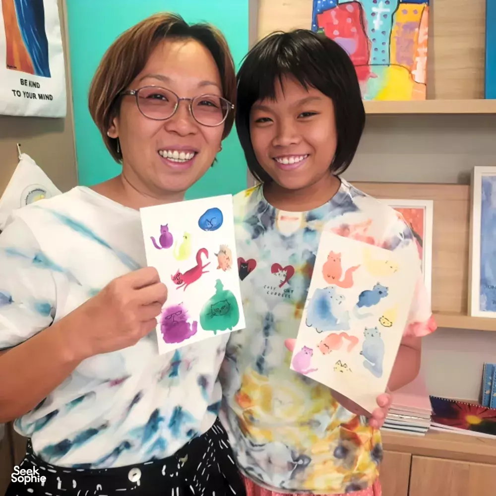 Art For Good art therapy in Singapore: two participants proudly holding painted animal cards during workshops in Singapore
