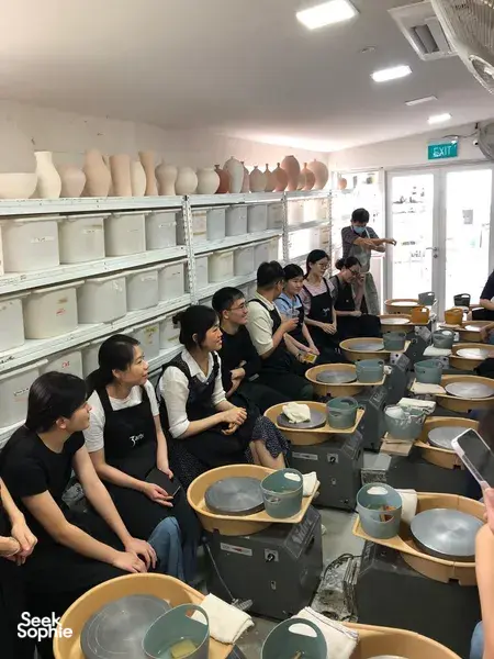 Sesi membentuk tembikar dengan roda putar di studio tembikar 3Arts di Singapura, pasukan kreatif duduk di roda tembikar untuk bengkel tembikar di Singapura