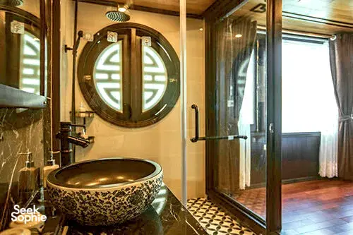 Traditional bathroom interior on Cat Ba Ocean Cruises with an ornate freestanding bathtub and arched mirror window, Lan Ha Bay