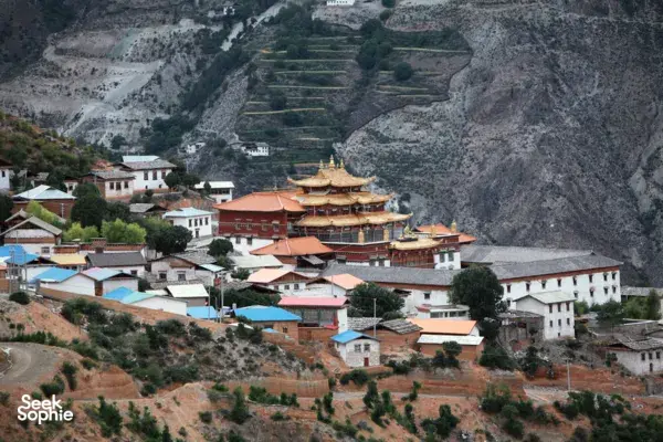 Terraced hillside village with multi-building Tibetan monastery complex and prayer halls in Shangri-La’s Meili region