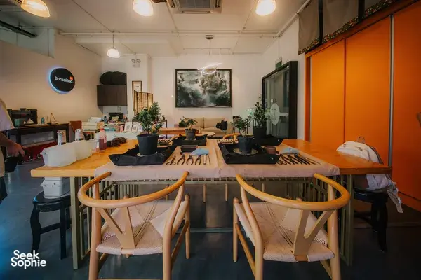 Japanese-style tropical bonsai workshop room in Singapore with empty chairs, worktables, tools and potted trees for arranging