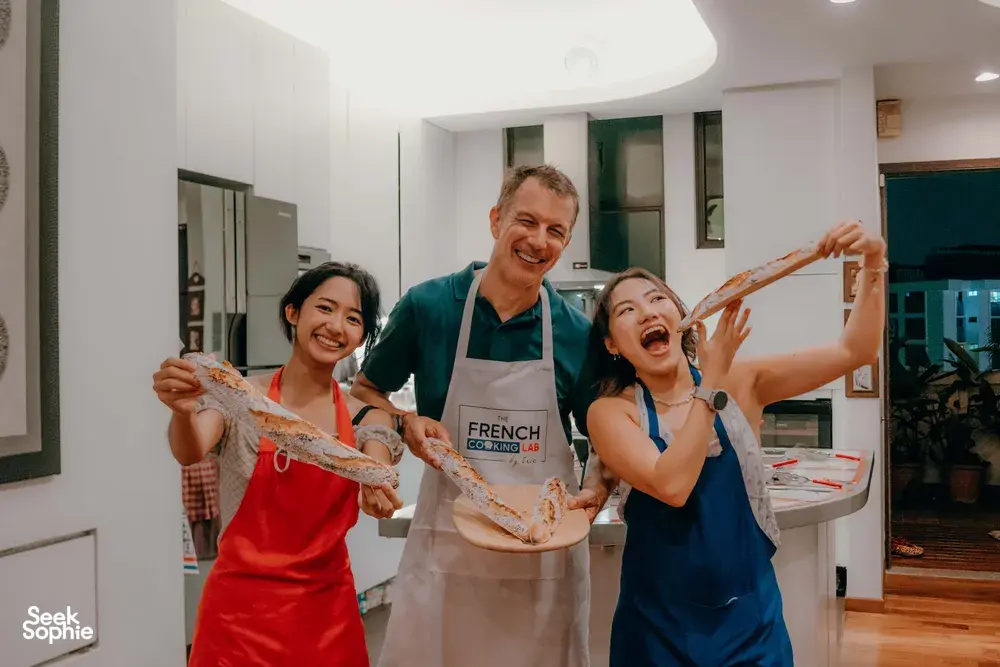 Singapore cosy loft French baguette workshop at French Cooking Lab: smiling guests holding flour-dusted baguettes, workshops in Singapore