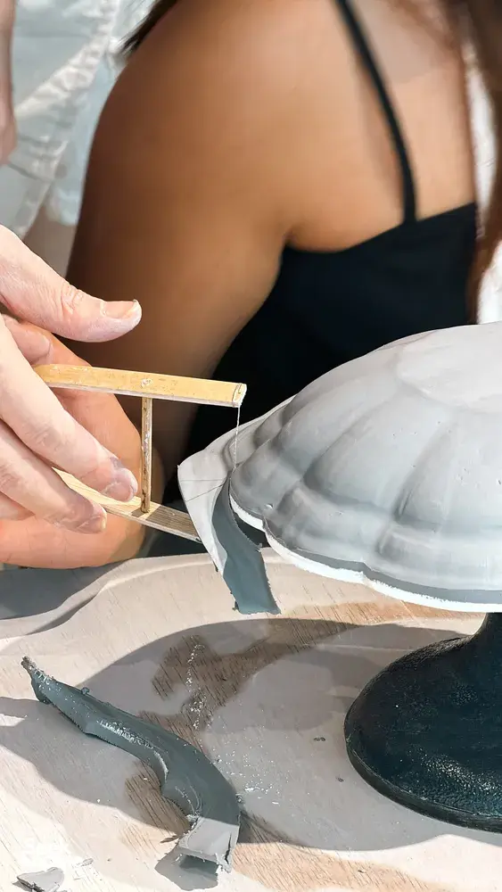 Ina Atelier potter hand-trimming an antique European-style ceramic plate during pottery workshops in Singapore