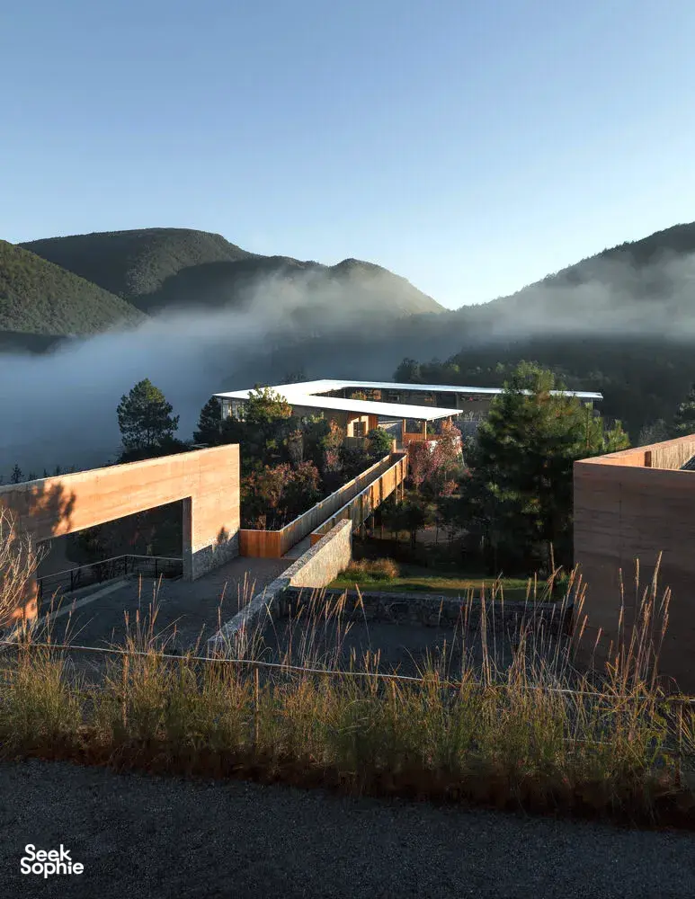 Halaman bangunan eco-retreat modern di Shaxi, Dali, dikelilingi punggung pegunungan berkabut saat fajar, menginap di Linden Centre