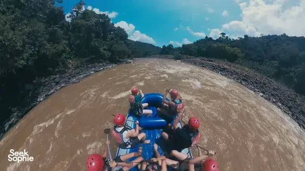 Rafting boat with paddlers in red helmets surging along a muddy river on a full-day Padas rafting trip with Xtreme Paddlers
