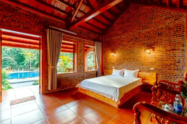 Cozy bedroom inside Ninh Binh Family Homestay with a stone-tiled floor, wooden beams and a view onto the pool