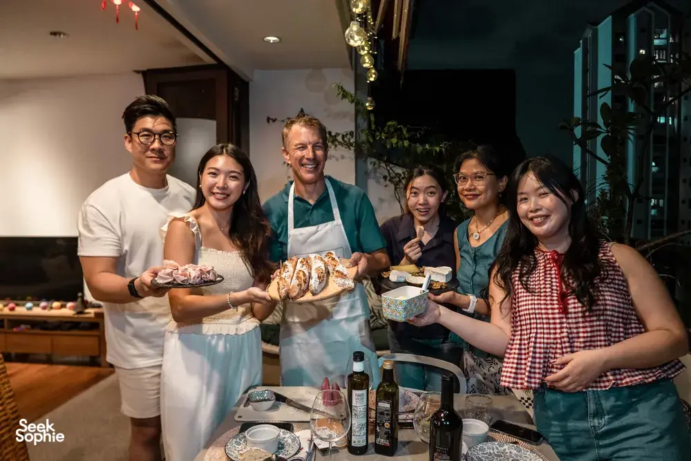 Small group in aprons celebrating French baguettes and drinks in a cosy loft private dining Singapore