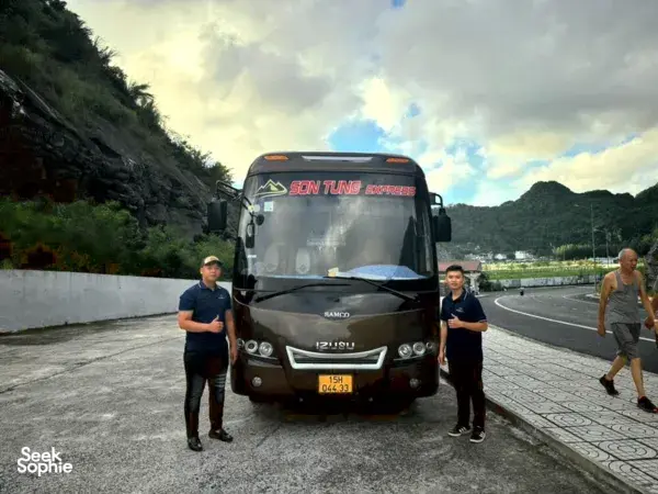 Front view of Son Tung Express coach bus for Cat Ba to Halong Bay transfers, parked by a curving road in Vietnam