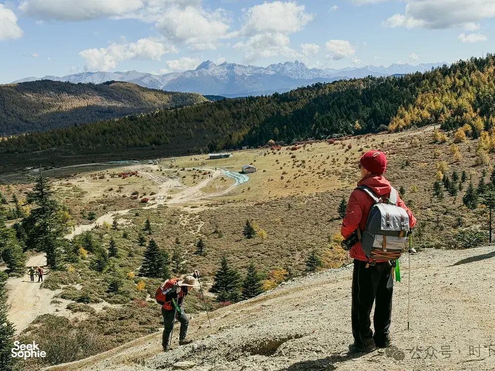 Hiker with a backpack overlooking a turquoise alpine lake basin in Shangri-La during the 2D1N trek towards Tiger Leaping Gorge