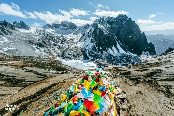 Colourful prayer flags overlooking snow-capped peaks and a valley in Shangri-La, along the Tiger Leaping Gorge trek