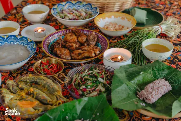 Kota Kinabalu Indigenous Sabahan cooking feast spread with grilled meat, herbs and steaming bowls on a patterned table